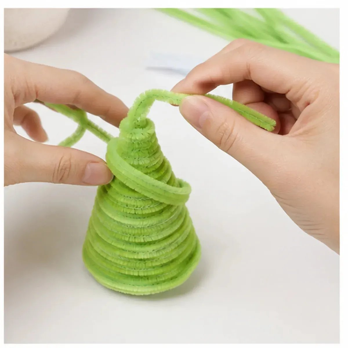Hands building pipe cleaner Christmas tree